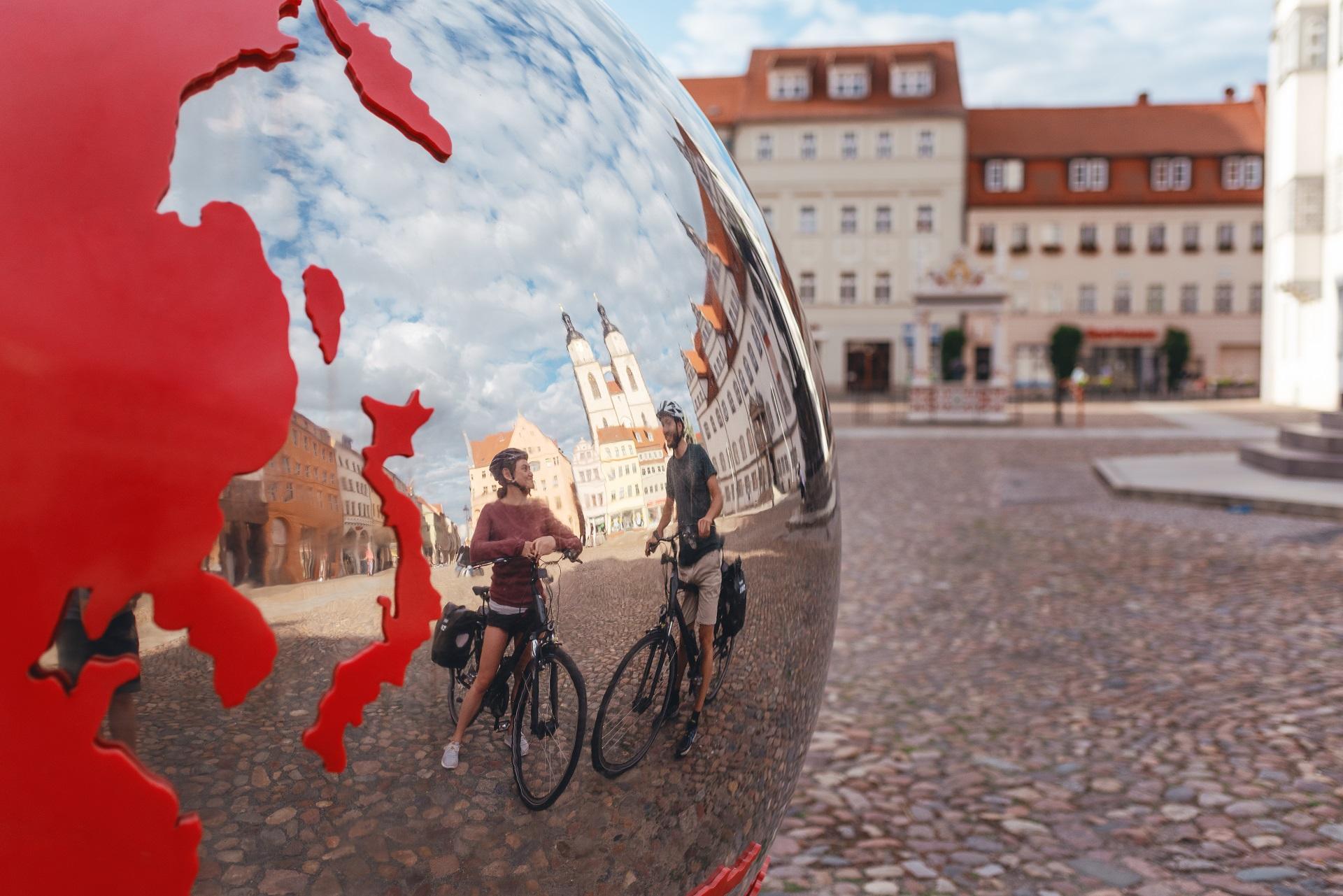 Radfahrer vor der Weltkugel am Marktplatz WIttenberg